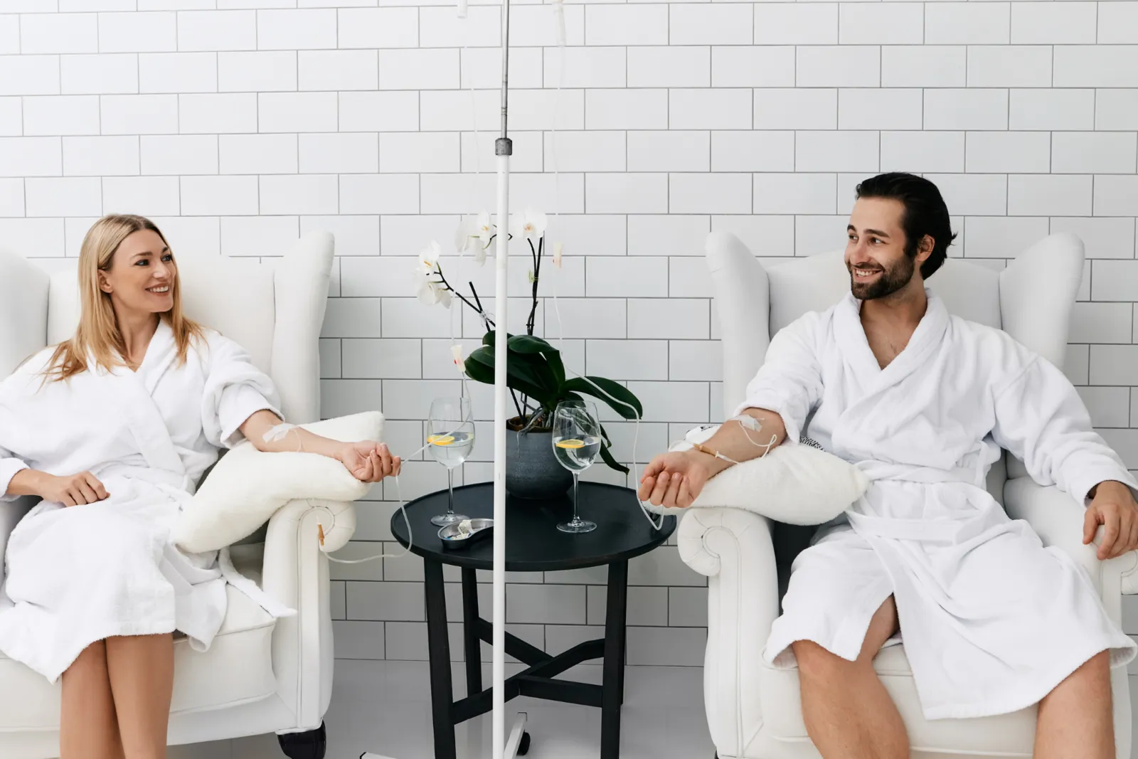 Man and woman in white robes relaxing in armchairs during NAD+ IV drip therapy