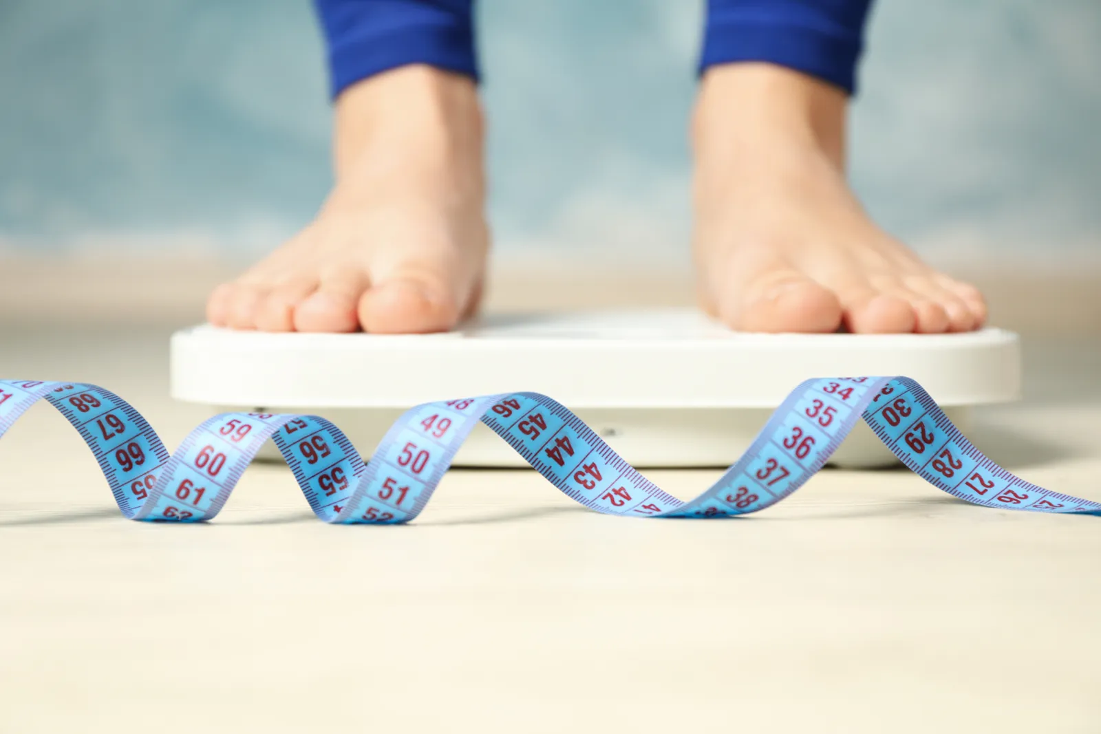 Feet on a bathroom scale with a measuring tape