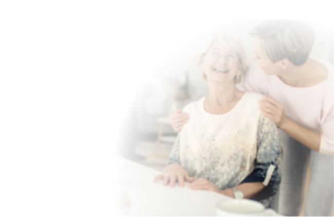 Betreuerin umarmt eine lachende Seniorin zu Hause, Seniorenbetreuung in Salzgitter