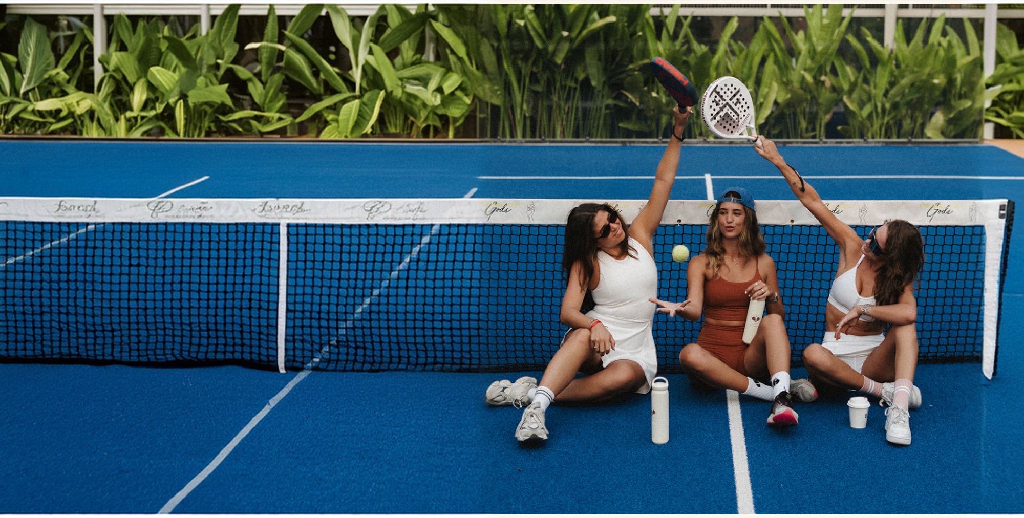 Players mid-rally on a floodlit padel court