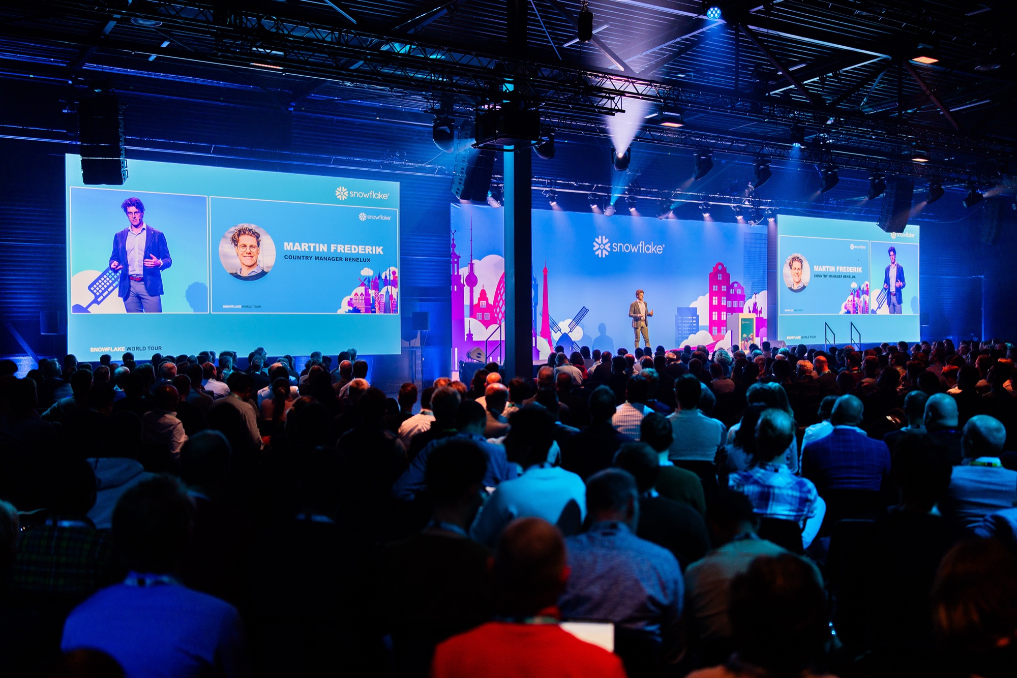 A packed crowd lit by stage light at a live event