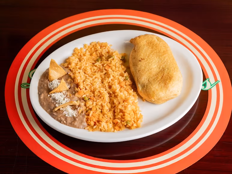 Plate with Mexican rice, refried beans topped with cheese and tortilla chips, and a fried stuffed taco.