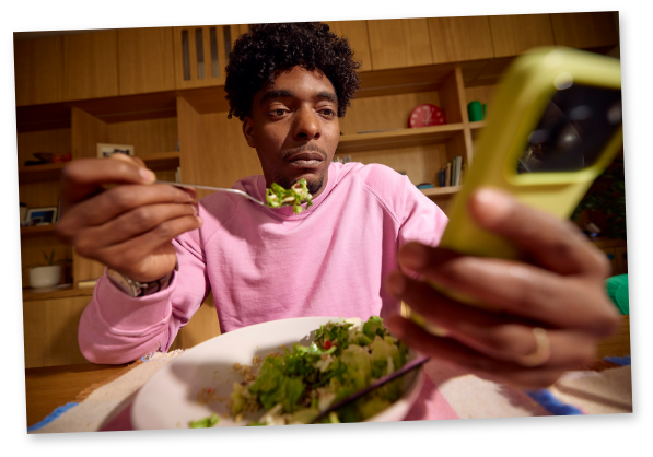 Man eating a salad while looking at his phone