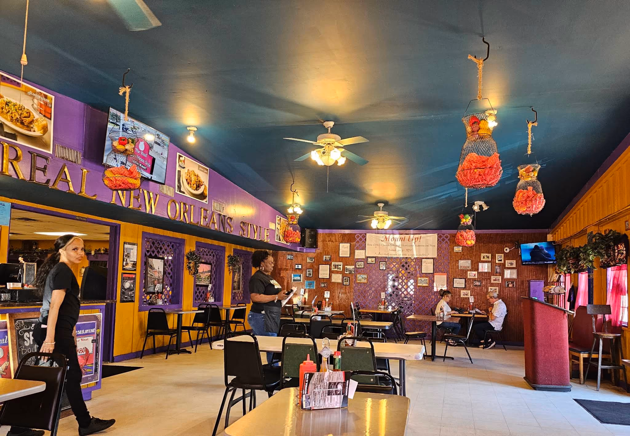Interior of a colorful New Orleans style restaurant with purple and yellow walls and hanging baskets.