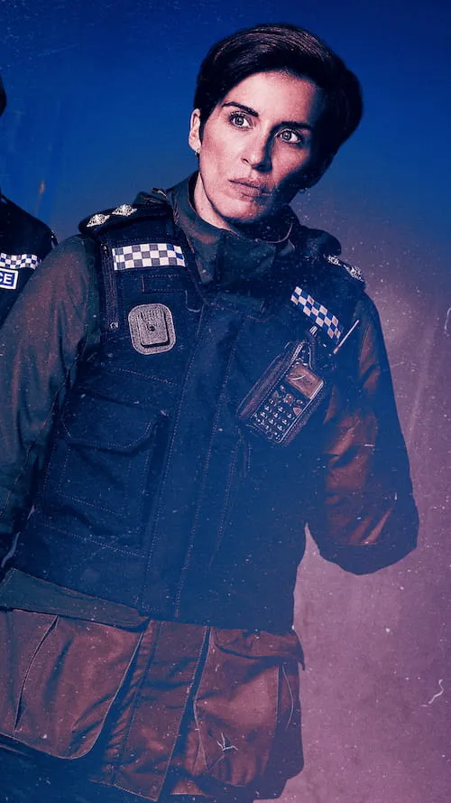 Woman police officer wearing a black tactical vest with radio and checkered insignia on dark uniform, looking alert against a dark background.