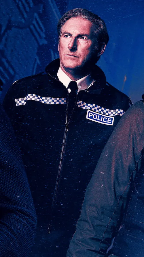 Serious middle-aged male police officer with slicked-back hair wearing a black jacket with a blue and white checkered pattern and a police badge, looking to the side against a dark blue background.