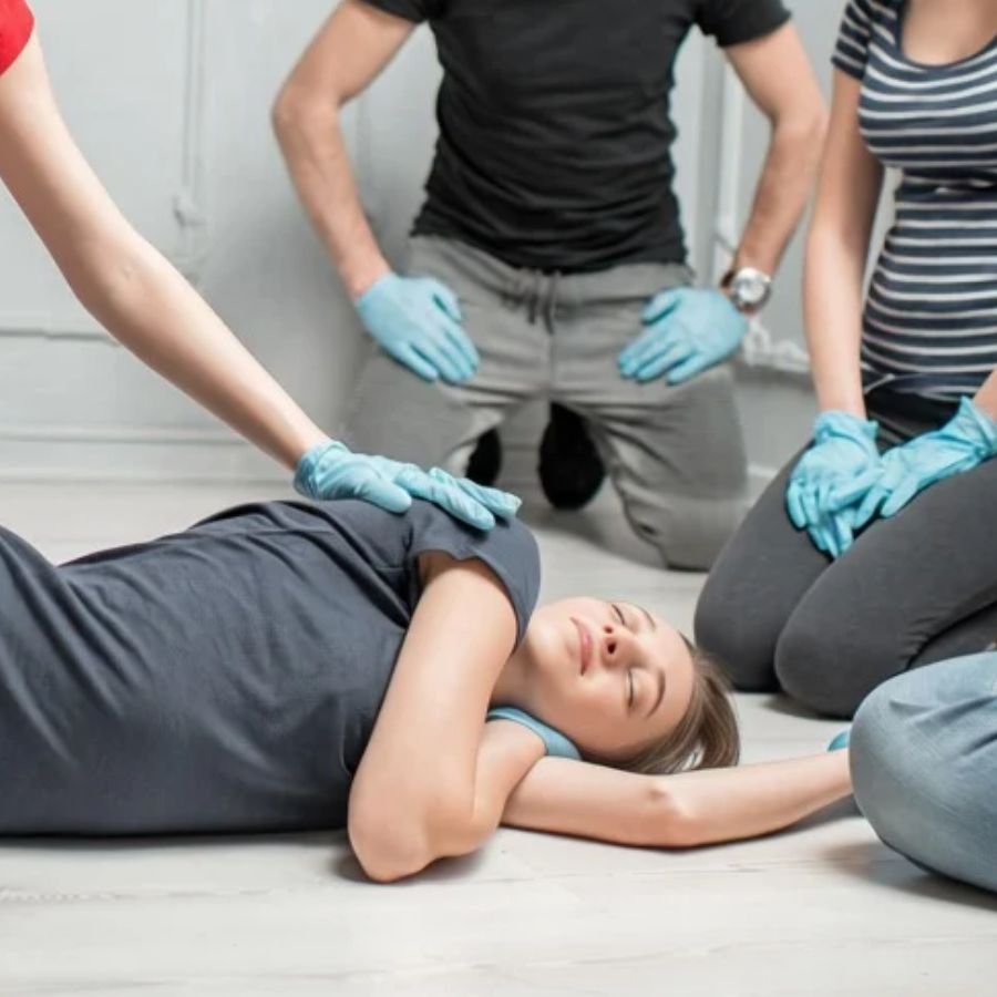A group of students wearing nitrile gloves gathered around a volunteer receiving treatment.