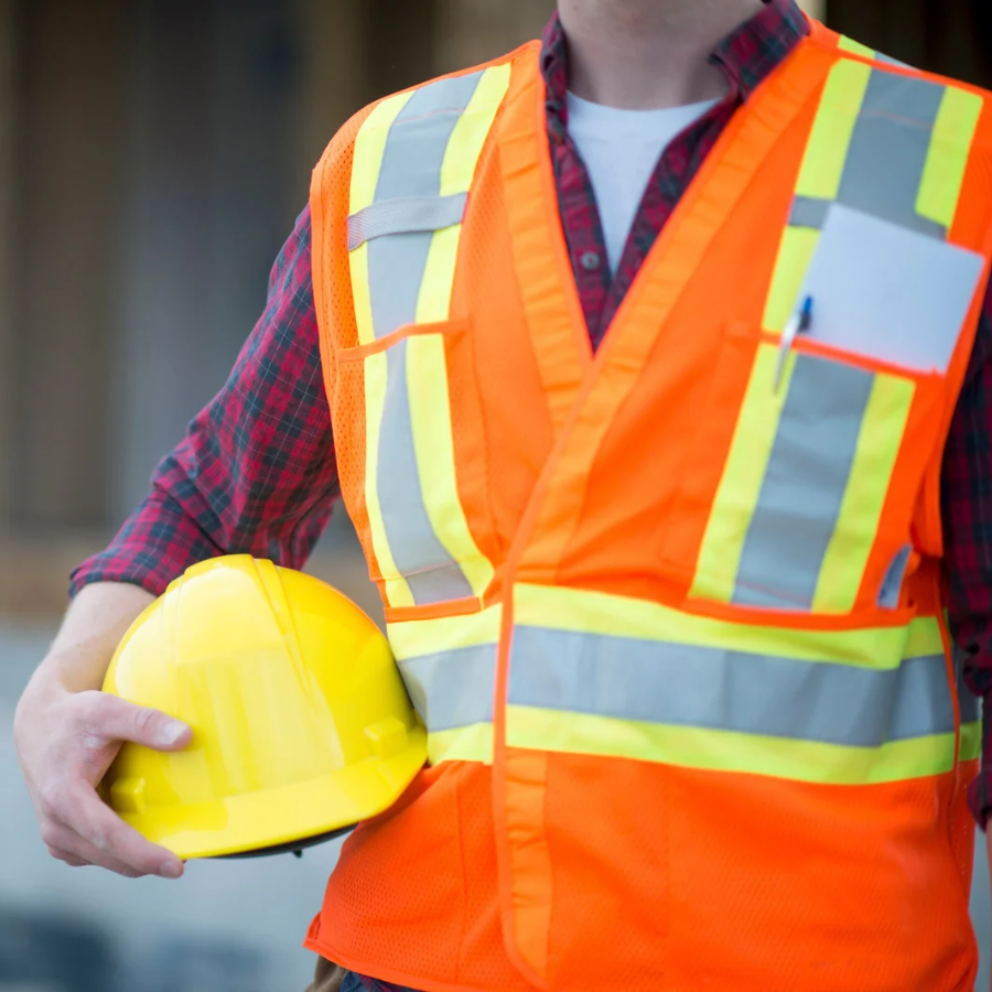 A safety manager in a hi-vis vest, holding a hard hat