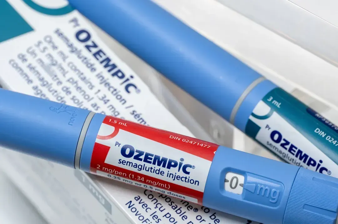 Close-up of two blue Ozempic semaglutide injection pens, one with a red label indicating 1.5 mL and dose dial set to 0 mg.