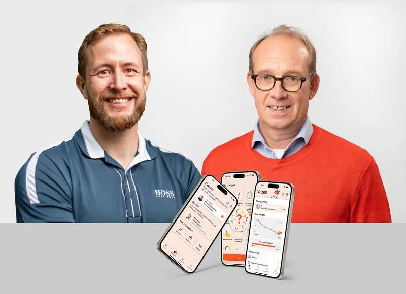 Two smiling men, one in a blue Hugo Boss polo and the other in an orange sweater and glasses, with three floating smartphones displaying a health and coaching app interface.