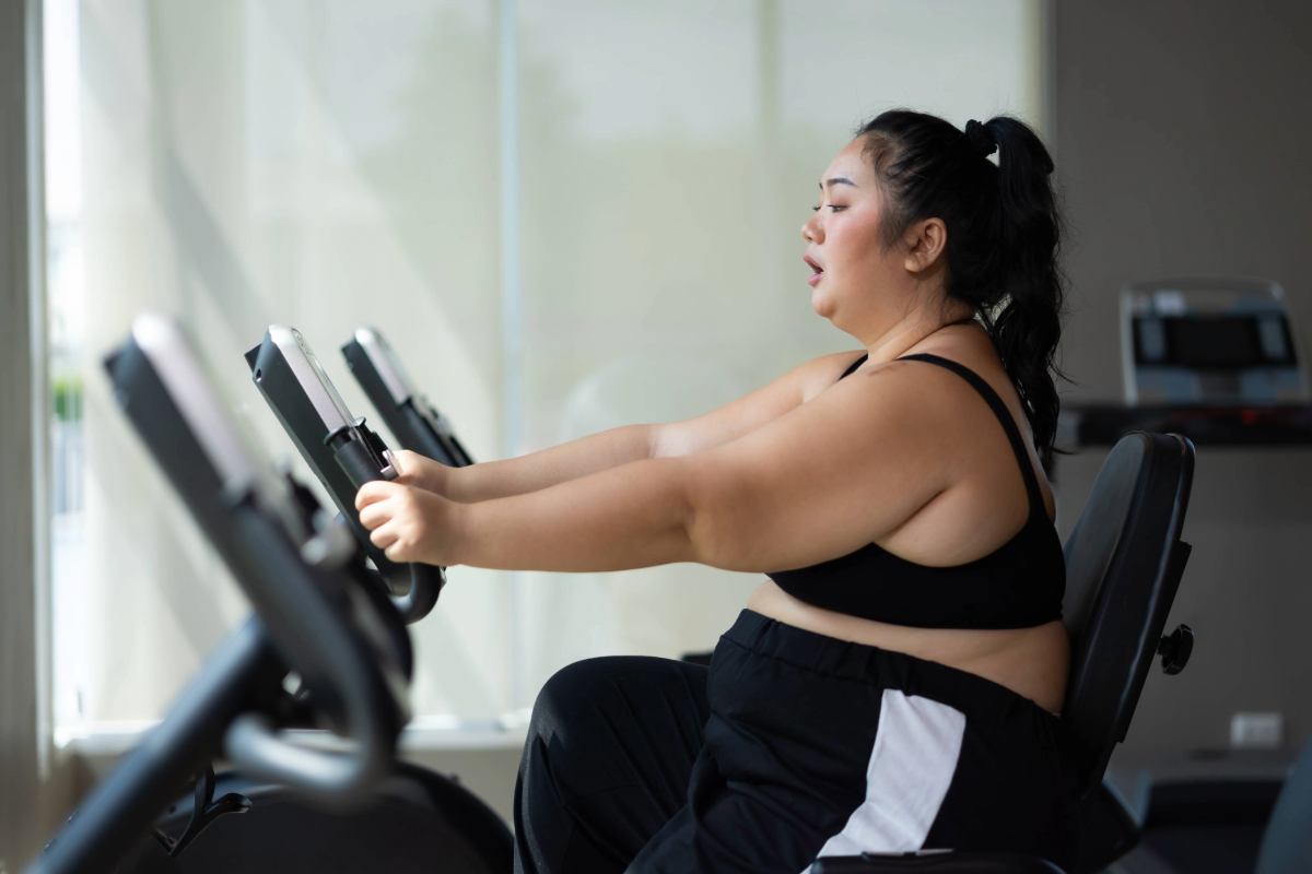 Woman exercising on a recumbent stationary bike in a gym.