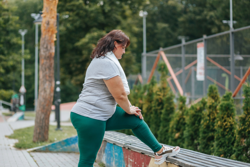 Een vrouw die staand stretcht bij een bankje