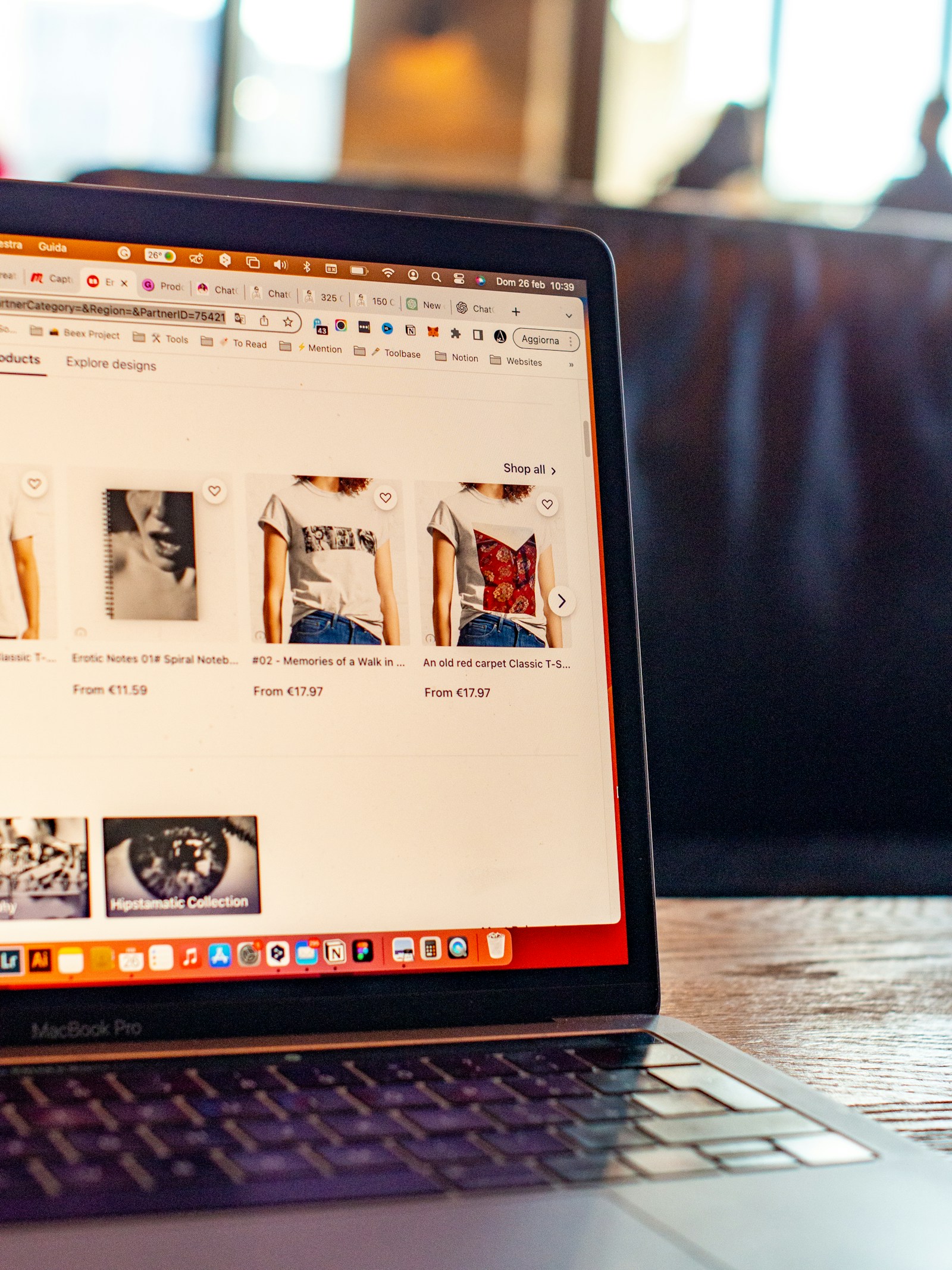 MacBook Pro laptop screen showing an online shop with T-shirts and notebooks for sale.