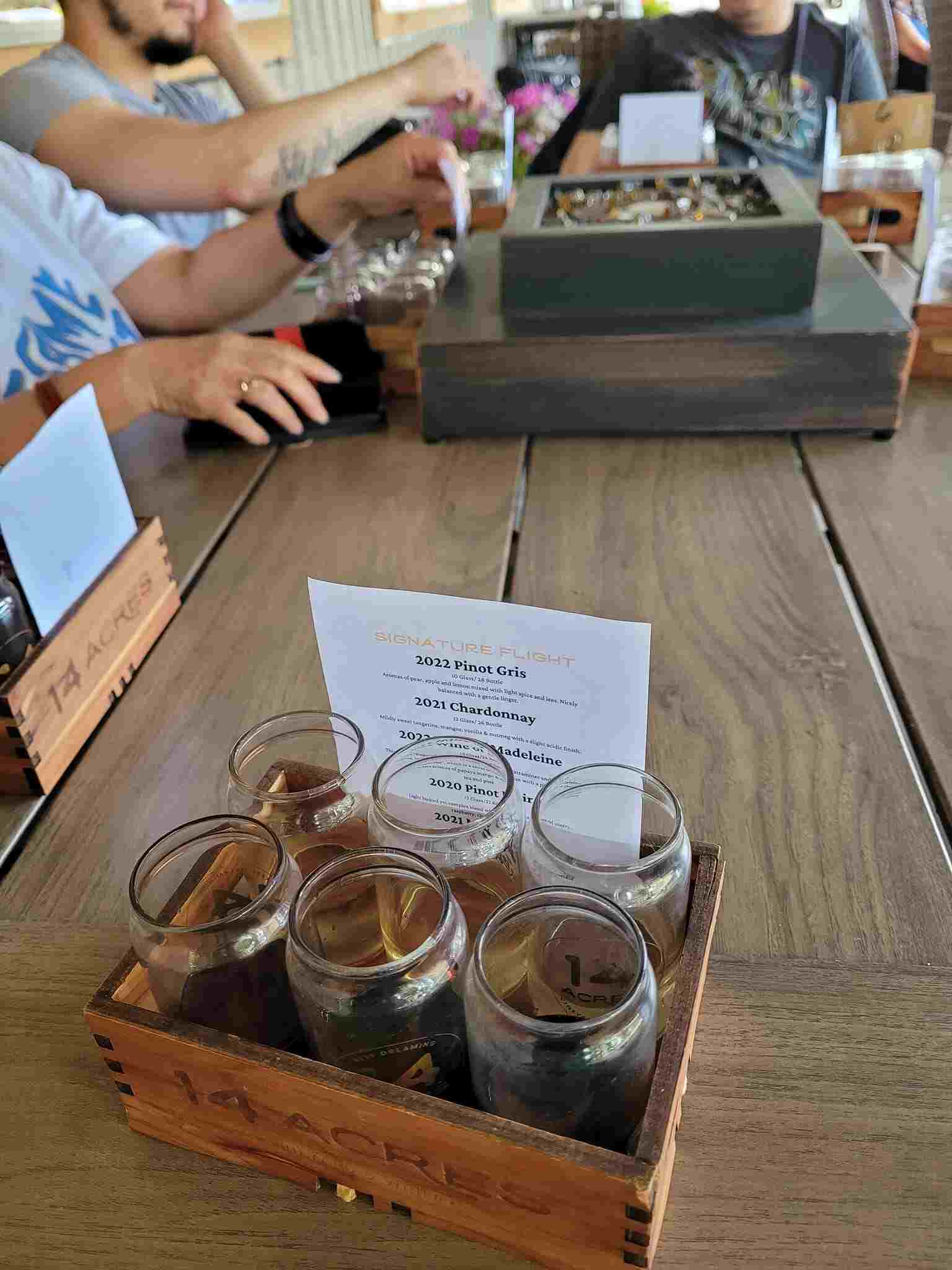 A wooden 14 Acres flight box with four tasting glasses and a printed tasting menu