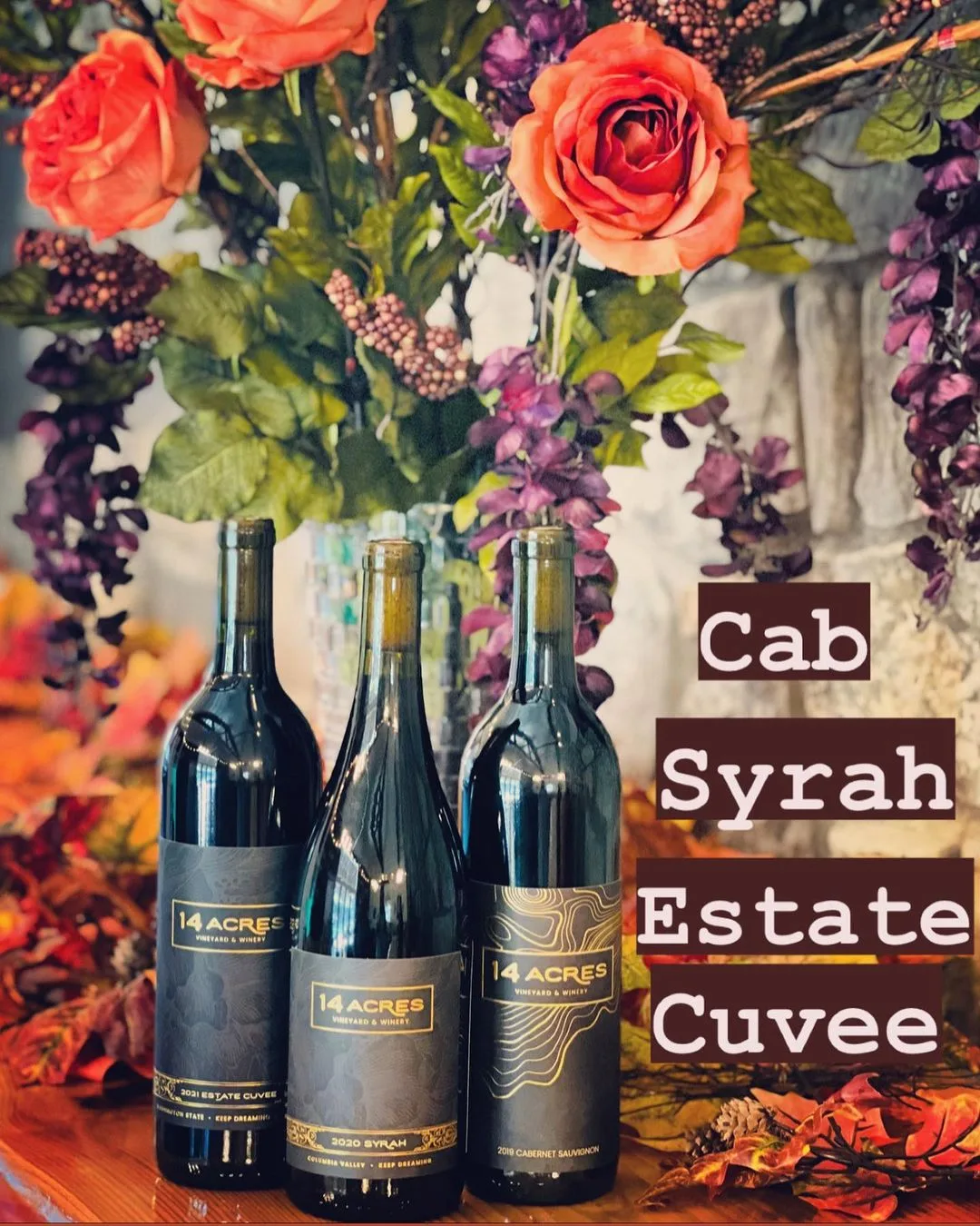 Three bottles of 14 Acres red wine — Cab, Syrah and Estate Cuvee — against a floral autumn backdrop