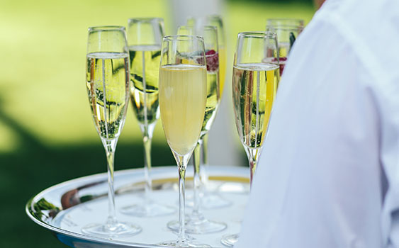 A server carrying a tray of sparkling wine flutes at an event