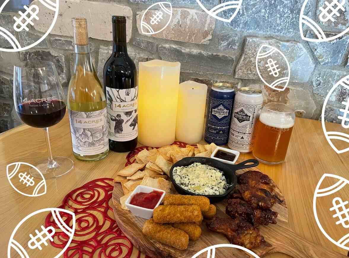A game-day spread of wings, dip and chips with bottles of 14 Acres red and white wine and candles
