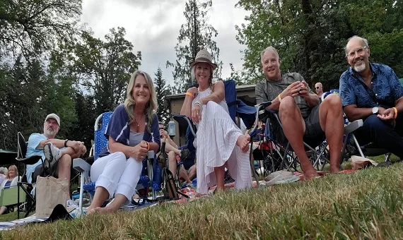 Four guests relaxing in camp chairs on the grass at an outdoor event at 14 Acres