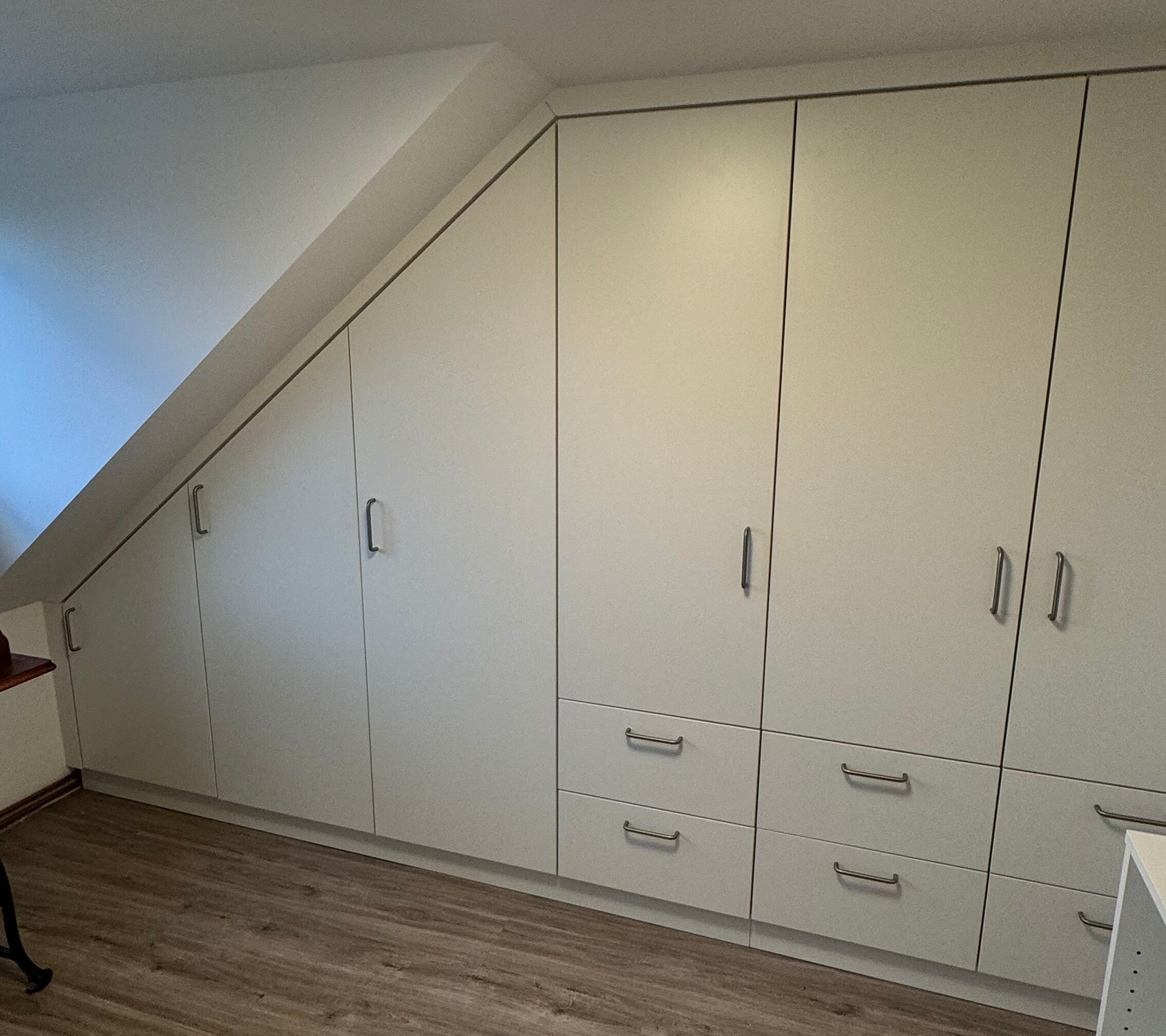 Weiße Schrankwand unter einer Dachschräge