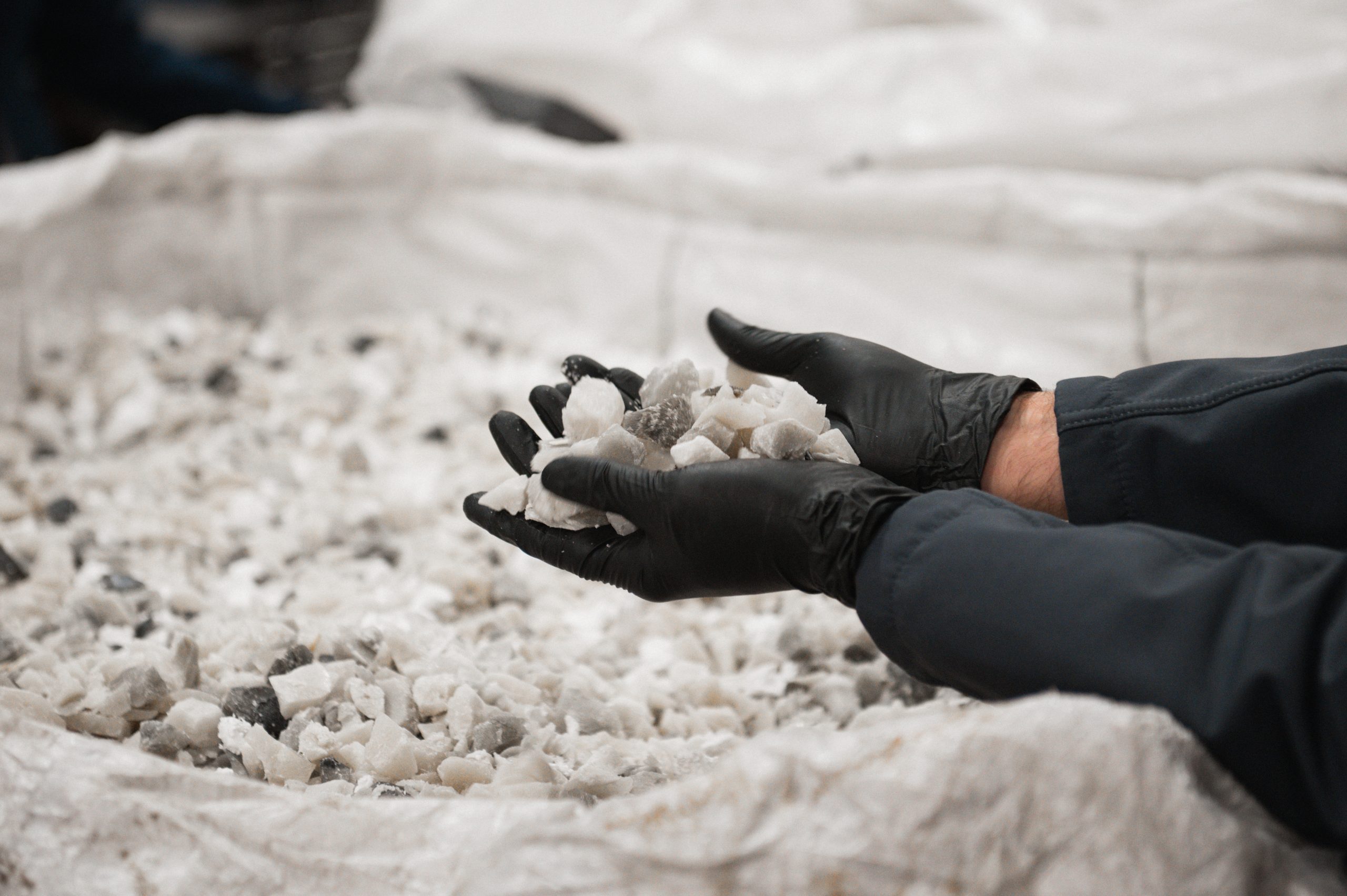 Gloved hands holding shredded plastic waste feedstock material used as recycling process input