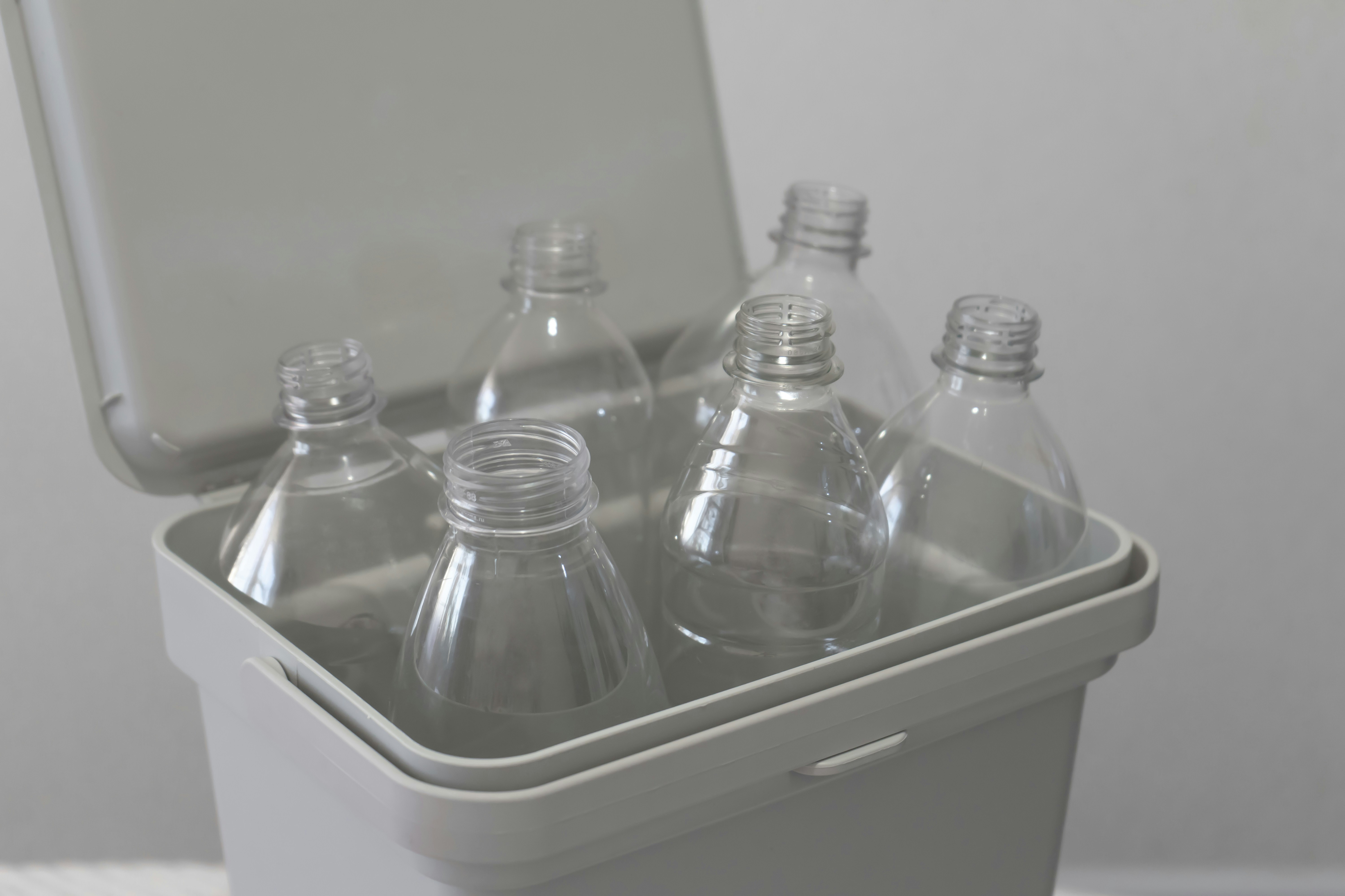 Empty clear PET plastic bottles collected together in a gray recycling bin