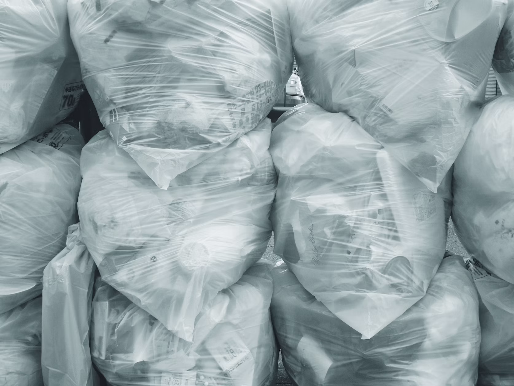 Stack of tightly bundled clear plastic bags filled with sorted household waste for recycling
