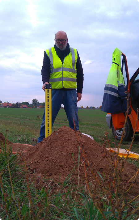 Vermessungsarbeiten mit Messlatte im Feld
