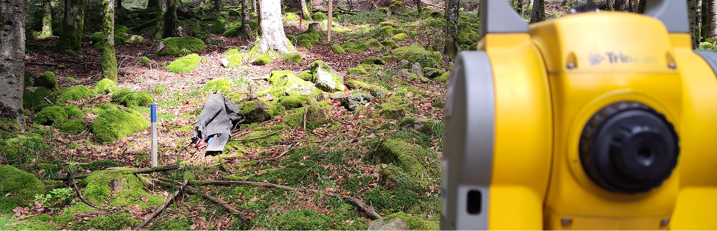 Nivelliergerät an einem Messpunkt im Wald