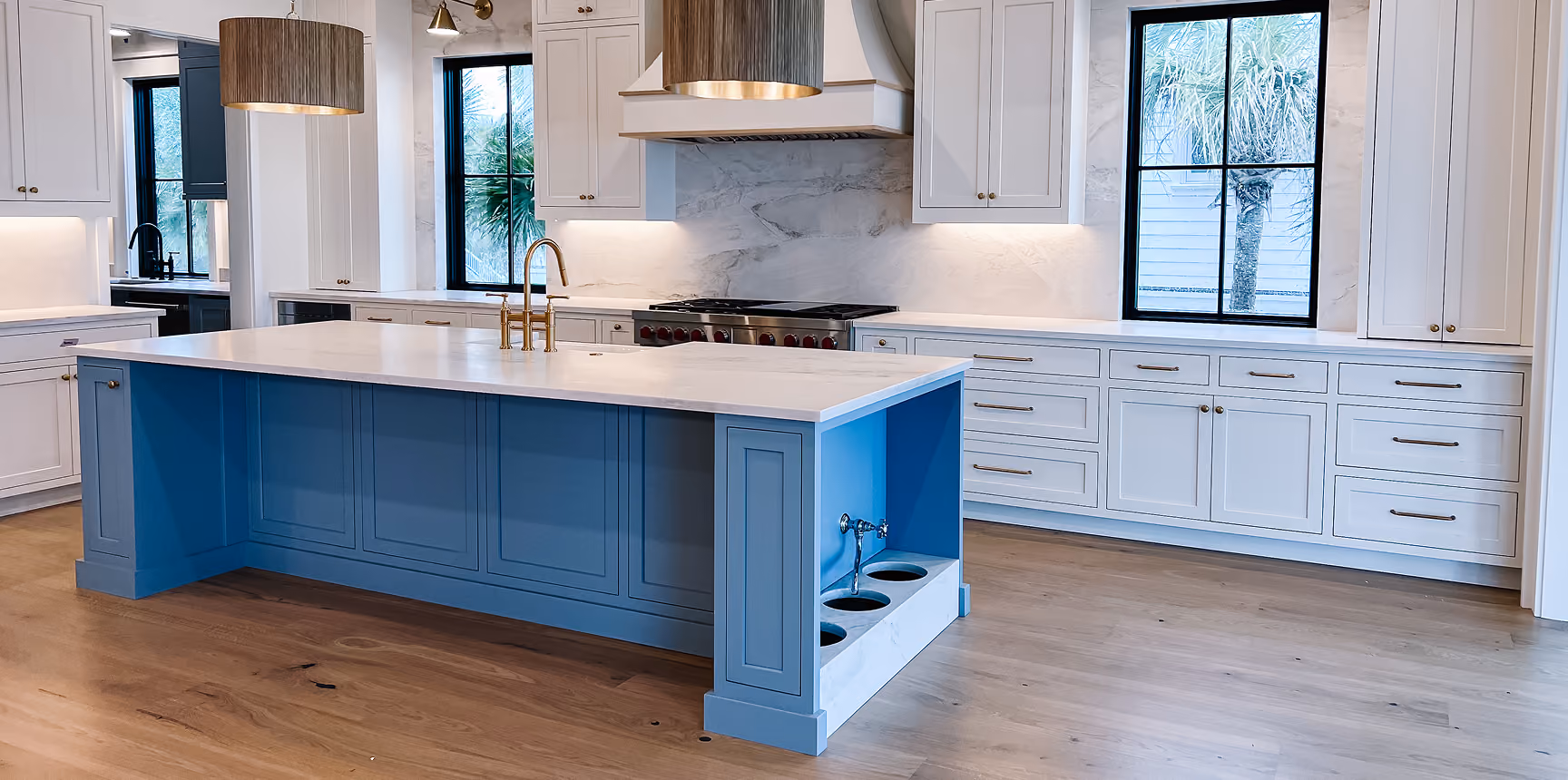 Modern kitchen with a blue island and wood flooring installed by Flooring Services LLC