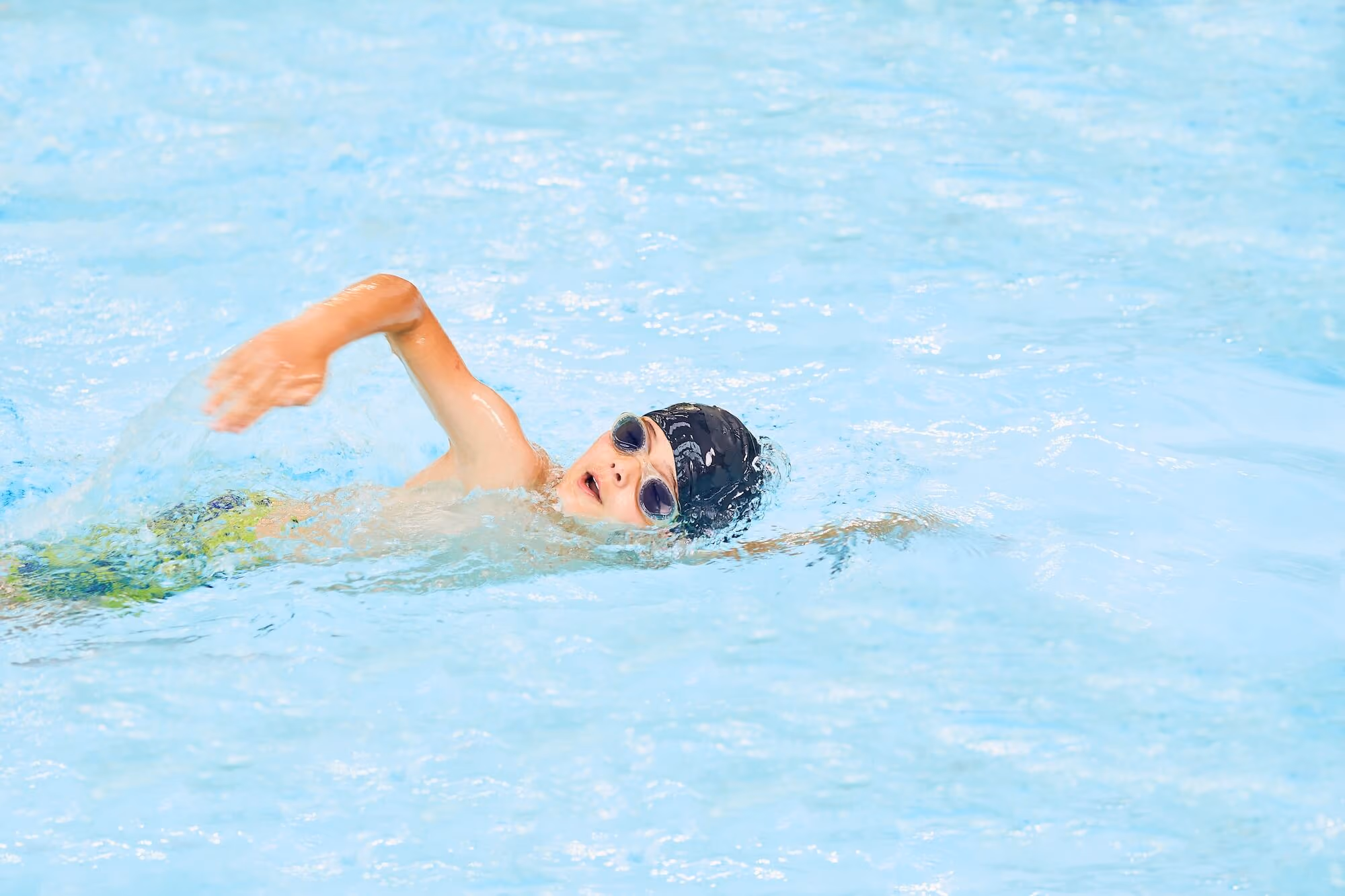 Young boy doing laps in pool.