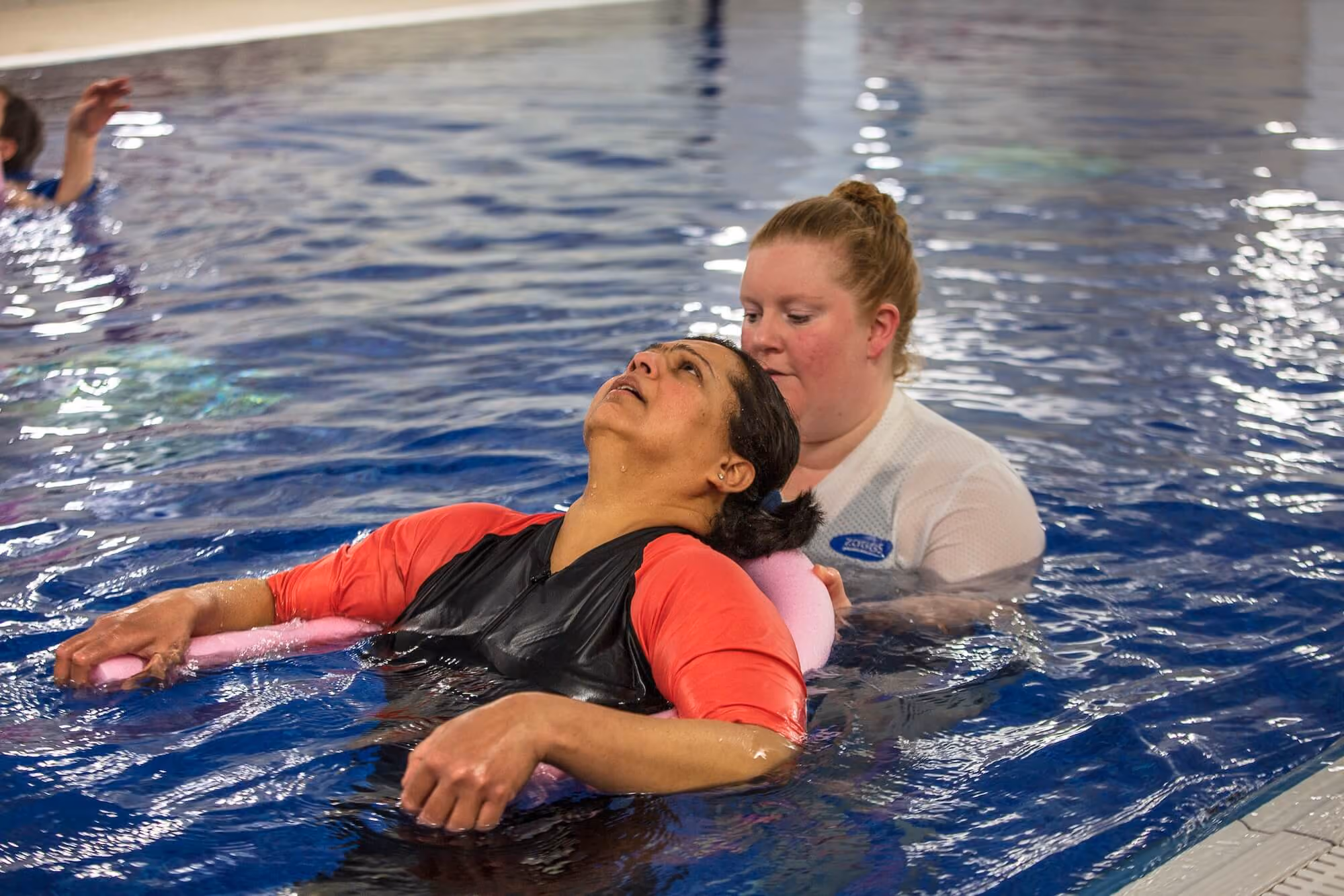 Adult woman learning to swim with instructor