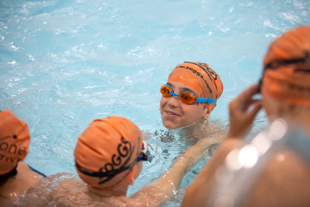 Children with orange swim caps swimming.