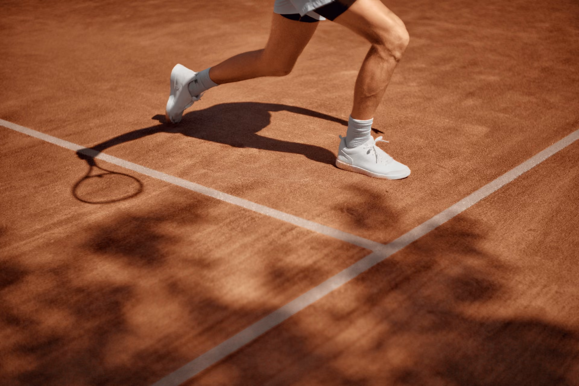 Tennis Players legs on a clay court.