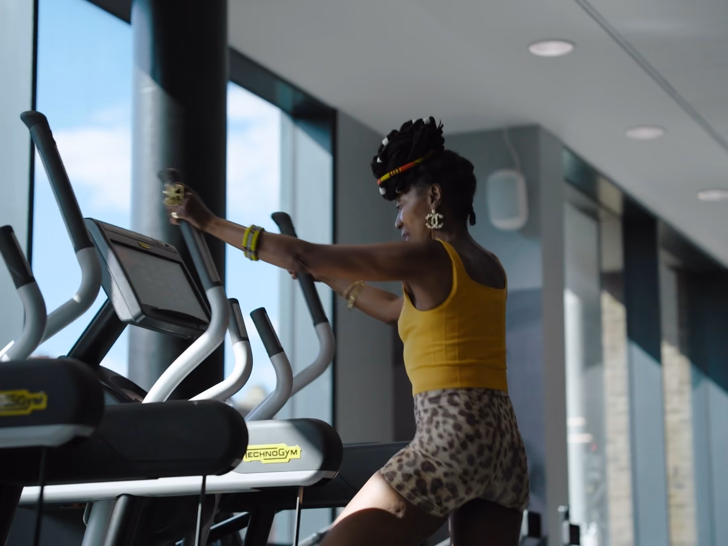 Woman on an elliptical in well lit gym room.