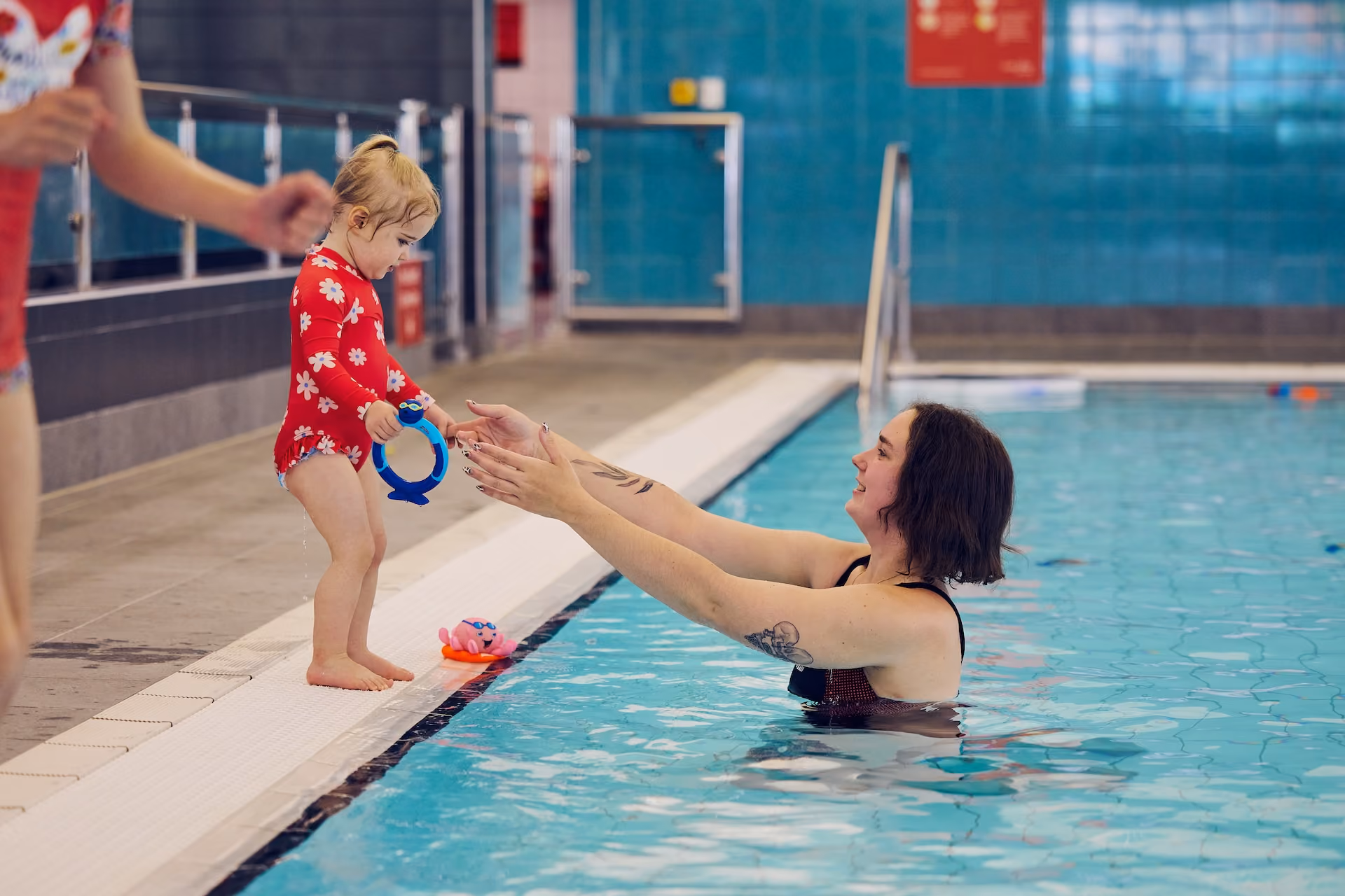 Woman prompting child to jump in the water.