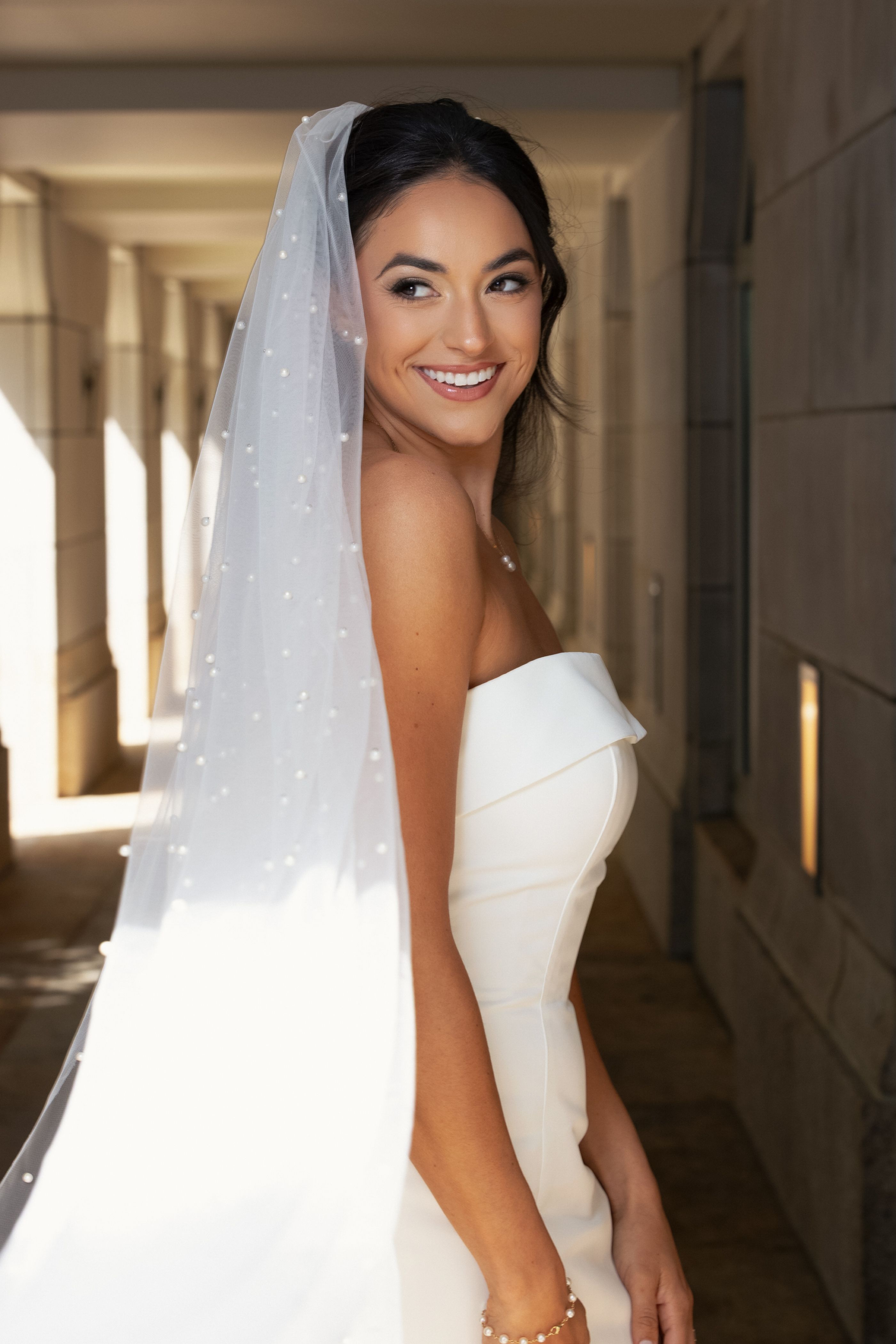 Bride in a pearl veil smiling over her shoulder