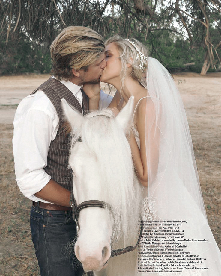 Couple kissing beside a white horse