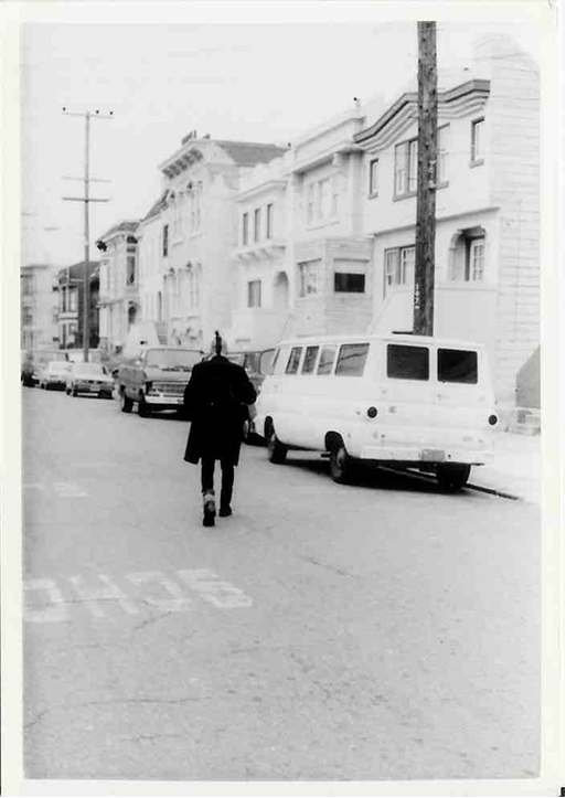 A black and white photograph of a punk walking down a city street.
