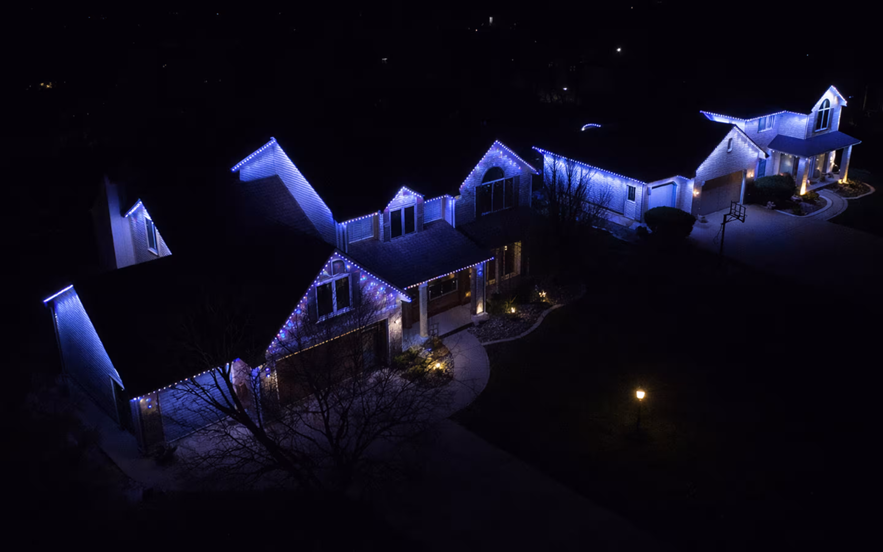 Drone shot of Manta permanent lighting on two homes next door both showcasing full wrap accent lighting at night 