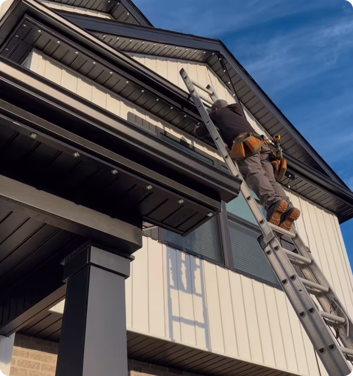 Permanent roofline lighting being installed on white home