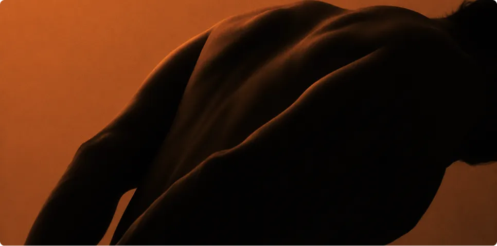Silhouette of a person's upper back and shoulder against a warm orange gradient background