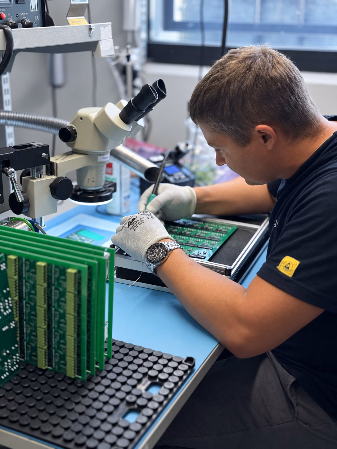 Pracownik Techbit wykonuje ręczny Rework płytki PCB pod mikroskopem.