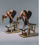 Two women performing a forward bend stretch on wooden Pilates chairs, wearing black workout clothes with hair tied back.