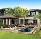 Modern house with large windows, lush lawn, and a rectangular outdoor pool with lounge chairs.