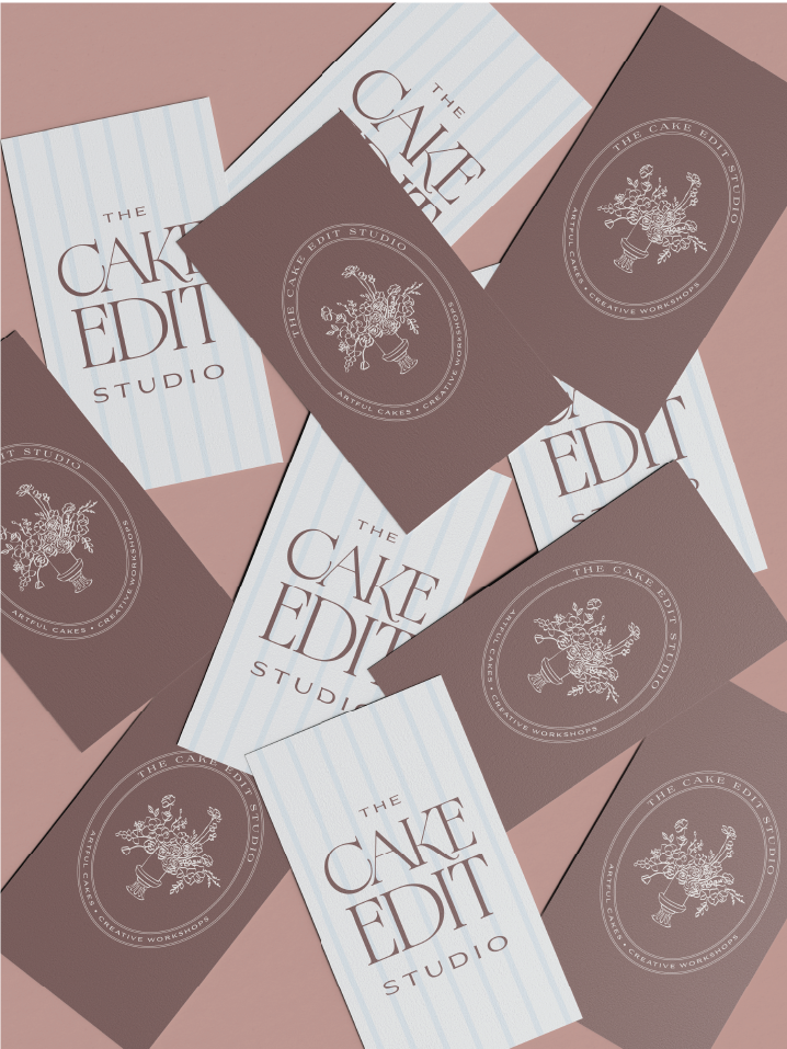 Scattered business cards on a pink background displaying 'The Cake Edit Studio' in elegant serif font and a floral vase logo with text 'Artful Cakes · Creative Workshops'.
