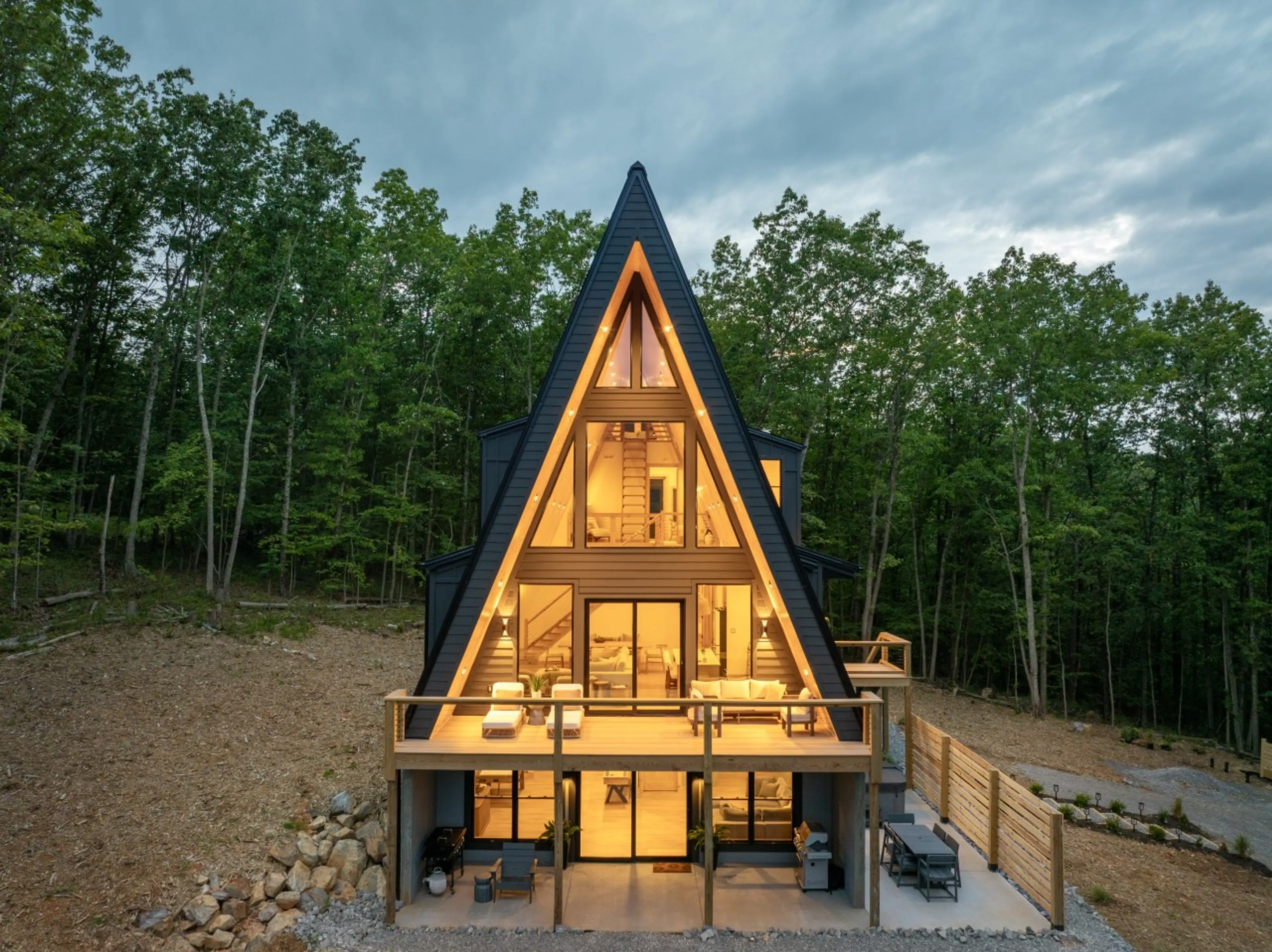 Solhaus Shenandoah A-frame cabin glowing at twilight, surrounded by forest