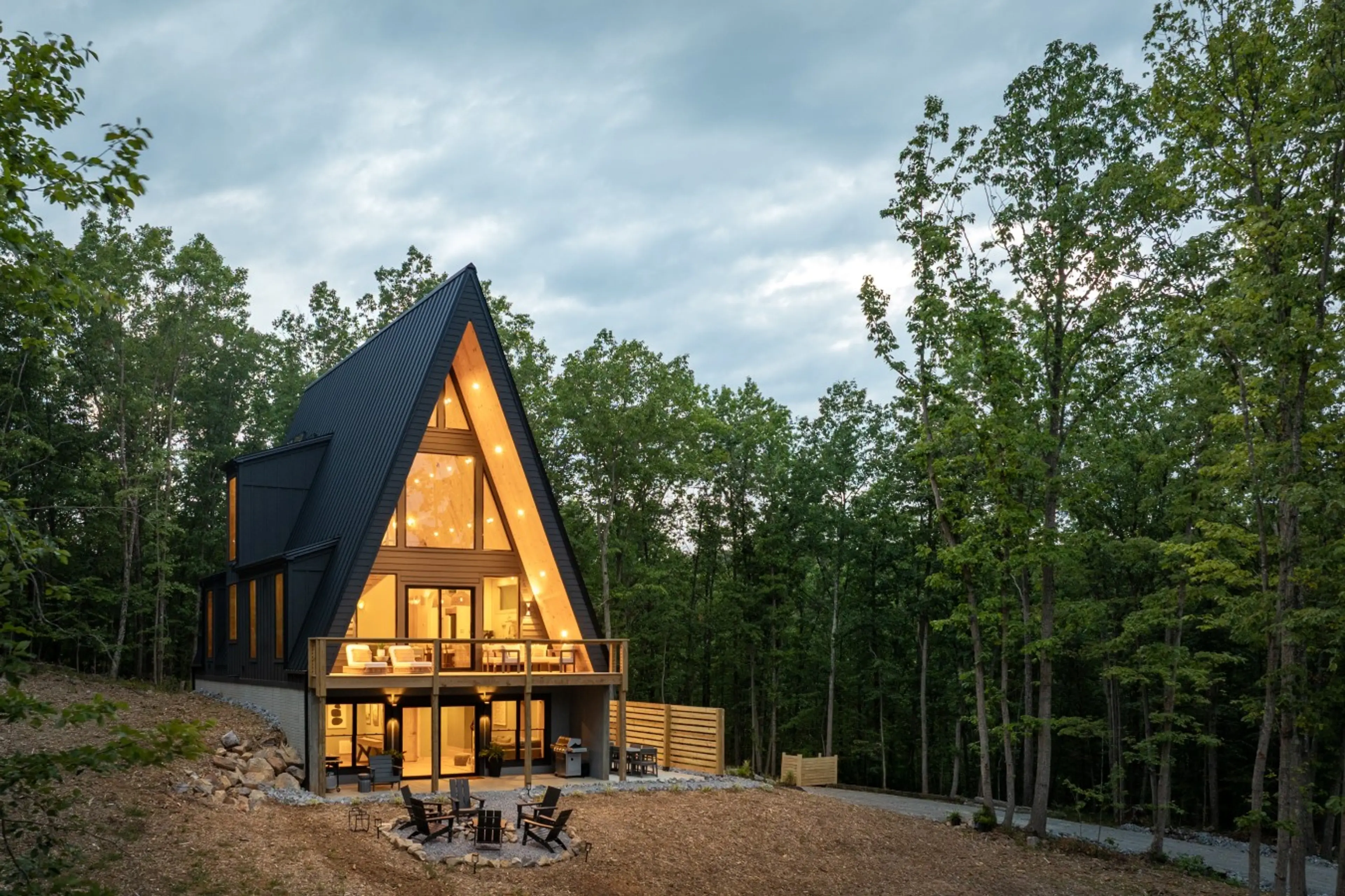 Twilight view of the Solhaus Shenandoah A-frame cabin glowing among the trees