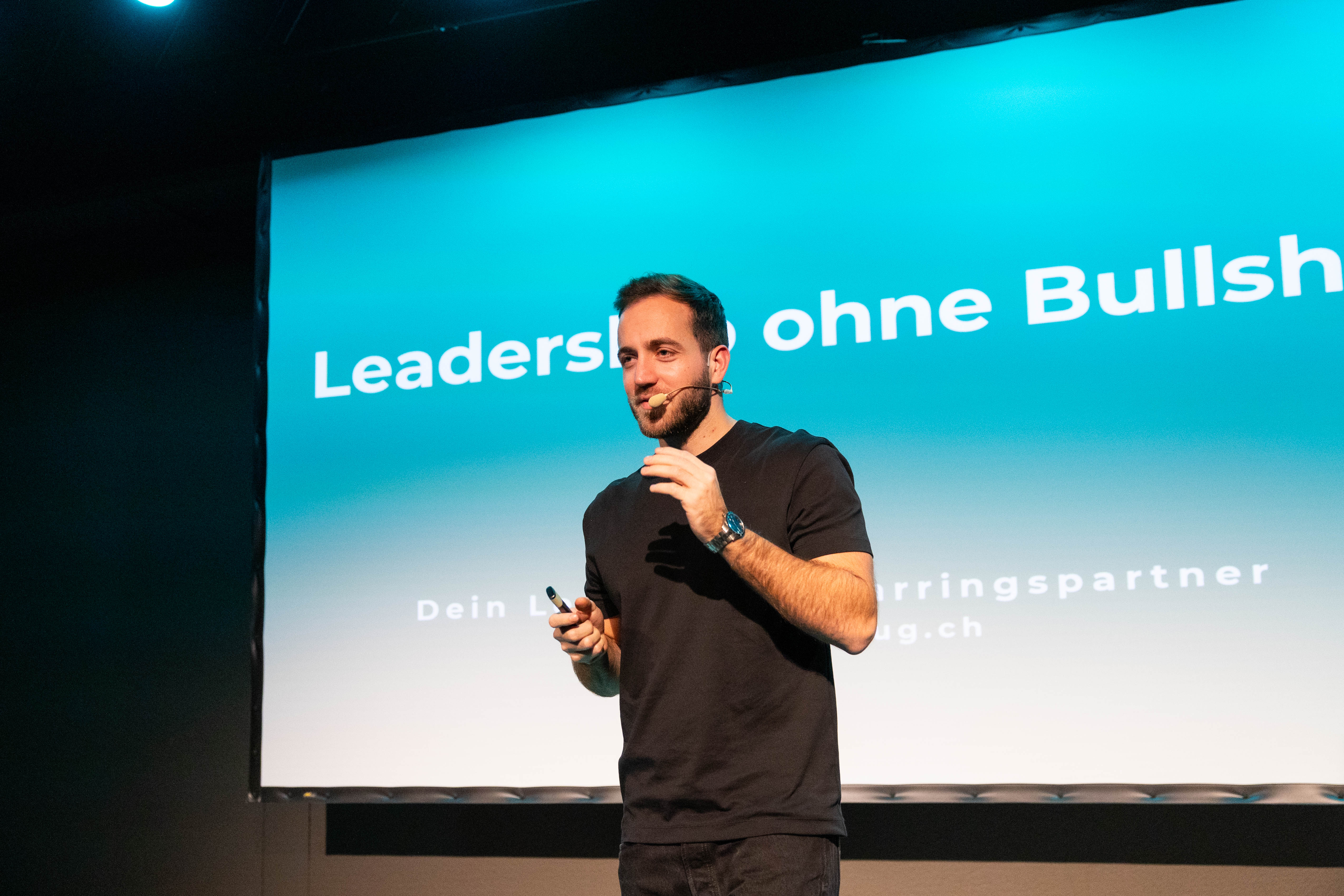 Lukas Hug auf der Bühne bei einer Keynote, im Hintergrund die Folie Leadership ohne Bullshit