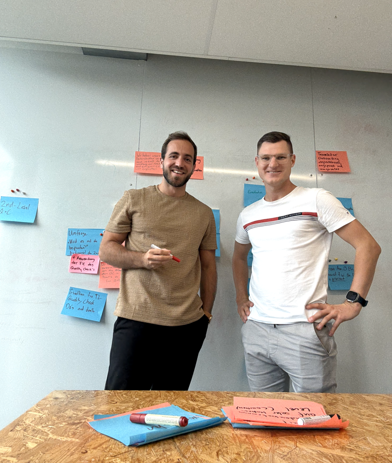 Lukas Hug und ein Teilnehmer vor einem Whiteboard voller Notizzettel während eines Workshops