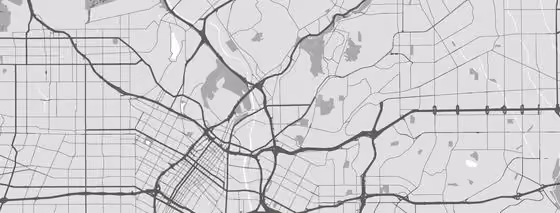 Black and white stylized map showing a network of roads and highways with varying thicknesses representing main and secondary routes across a city and its surrounding areas.